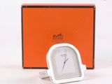 une horloge en argent posée devant une boîte orange