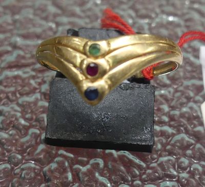 une bague en or avec un cordon rouge et une pierre bleue et verte