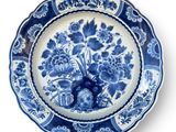 blue and white plate with flowers on it on a white background