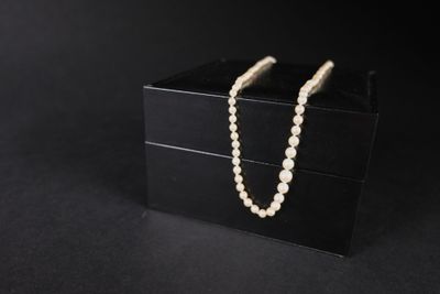 une boîte noire ornée d'un collier de perles, sur fond noir