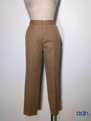 brown pants on a mannequin stand against a white wall