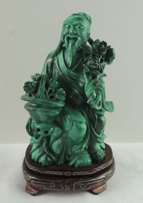 statue d'un homme assis sur un tabouret, tenant un panier de fleurs