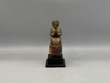 a small bronze statue of a woman sitting on a rock
