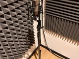 a microphone on a stand in front of a wall of sound foam