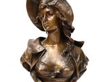 bronze bust of a woman wearing a hat and a dress