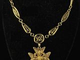a gold plated necklace with a cross pendant on a black mannequin
