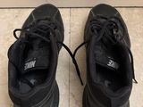 pair of black sneakers with laces on the soles on a tiled floor