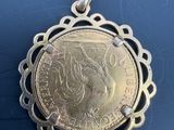 un pendentif en forme de pièce d'argent sur lequel est représenté le visage d'une femme