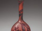 an orange vase with a design on it sitting on a white surface