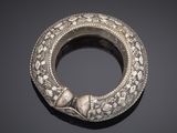 an antique silver bangle on a black surface with a black background