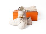 une paire de baskets blanches posée sur une boîte, à côté de deux boîtes orange
