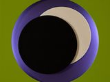a picture of a black and white half moon seen through a hole in a green wall