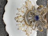 a white and gold plate with a blue stone in it