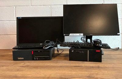 deux écrans d'ordinateur et un clavier posés sur une table en bois