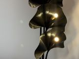 a black vase with three leaves on top of it