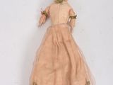 an old fashioned doll with a pink dress and hat on a white surface