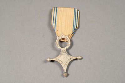 an old medal with a cross on it on a gray surface