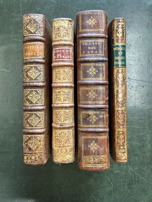 four old books are lined up on a green surface