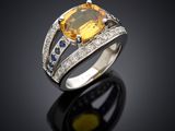 une bague sertie d'un saphir jaune et de diamants, posée sur un fond noir