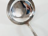 a silver spoon with a reflection of a person in it