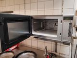 un micro-ondes à porte ouverte dans une cuisine où se trouvent des casseroles et des poêles
