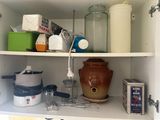 un placard de cuisine contenant une mijoteuse et d'autres ustensiles de cuisine