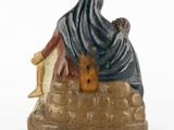 figurine of a man sitting on a rock with a dog in his lap