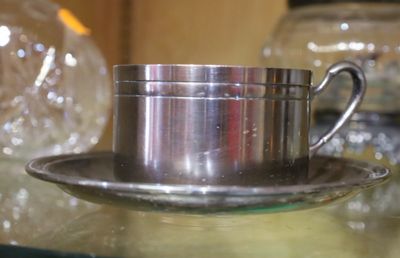 une tasse et une soucoupe en argent posées sur une table en verre