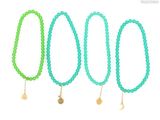 a set of four green bracelets with gold charms on them