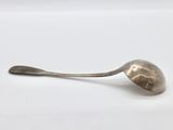 an antique silver spoon with a long handle on a white surface