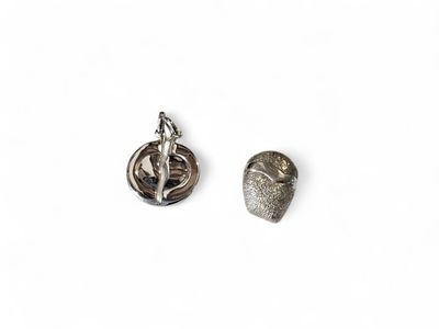 une paire de boucles d'oreilles en argent posées sur une surface blanche