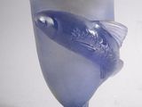 un vase bleu orné d'un poisson, posé sur un fond blanc
