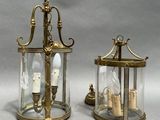 pair of brass and glass lanterns with candles inside of them