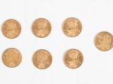 plusieurs pièces d'or sont disposées en cercle sur une surface blanche
