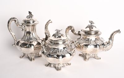 trois théières en argent posées sur une surface blanche