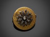 une photo d'une broche en or et diamants posée sur une surface noire