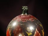 a red and black vase sitting on a purple surface