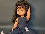 a doll that is sitting on the floor next to some clothes