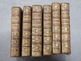 six vieux livres sont empilés sur une table