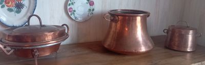 de nombreuses casseroles et poêles en cuivre posées sur une étagère en bois