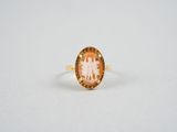 une bague en or ornée d'une pierre orange et blanche au centre
