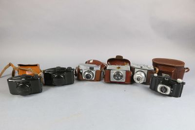 several cameras are lined up in a row on a white surface