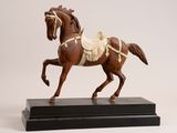 statue of a brown horse with a saddle on a black base