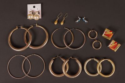 plusieurs paires de boucles d'oreilles créoles en or et de boucles d'oreilles posées sur un fond noir
