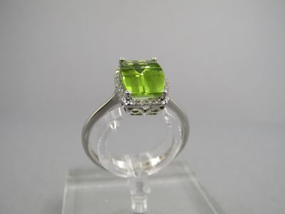 un gros plan d'une bague ornée d'une pierre verte posée sur un support transparent