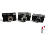 three cameras sitting next to each other on a white surface
