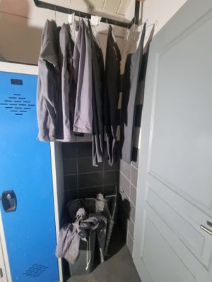 un casier bleu dans un coin d'une pièce, avec des vêtements suspendus dessus