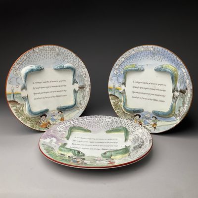 trois assiettes sur lesquelles est inscrit un poème, disposées les unes à côté des autres