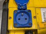 a blue electrical outlet on a yellow box in a warehouse