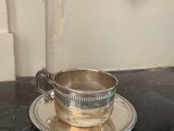 une tasse et une soucoupe argentées posées sur une table noire